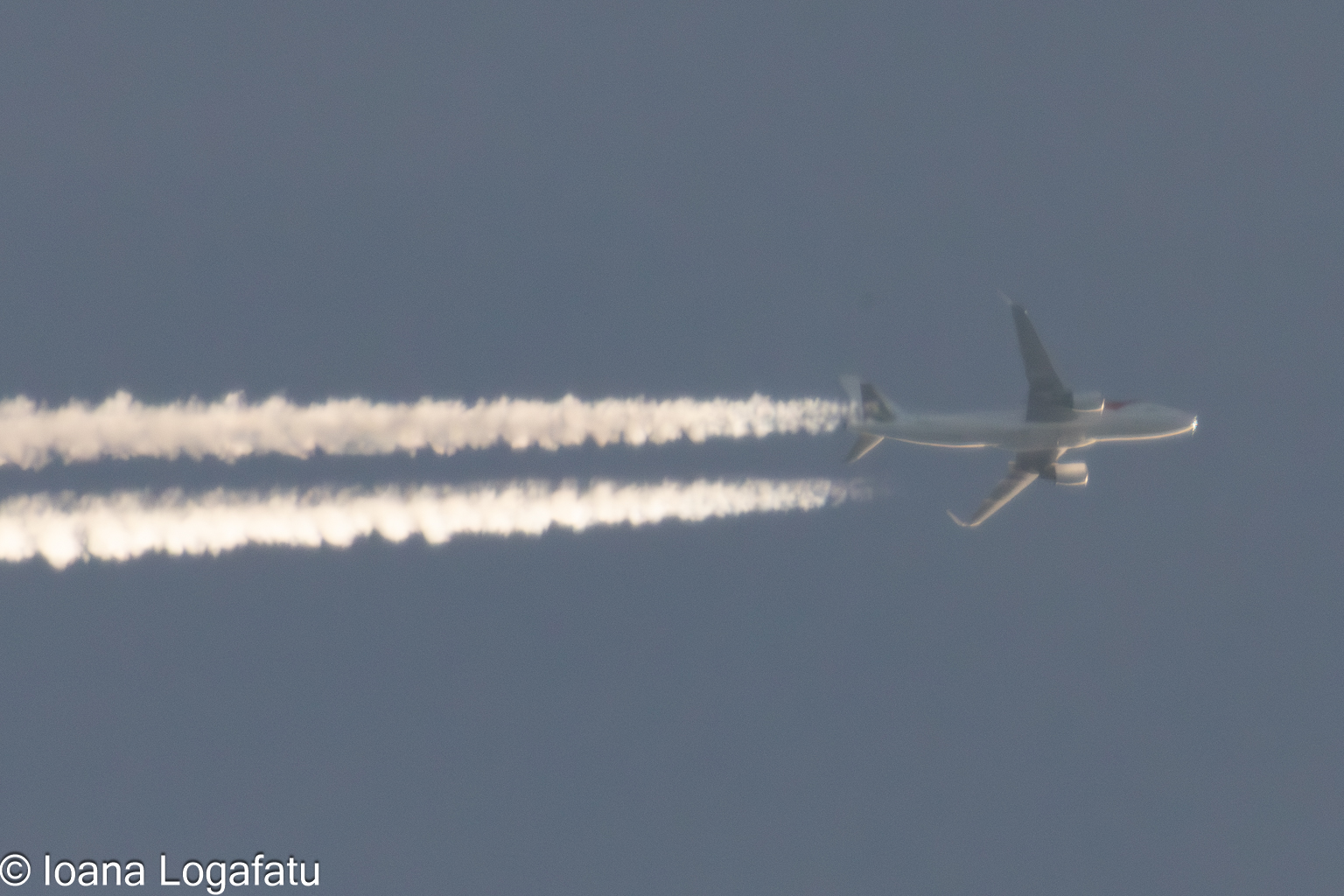 Jet soaring through a clear blue sky with trails